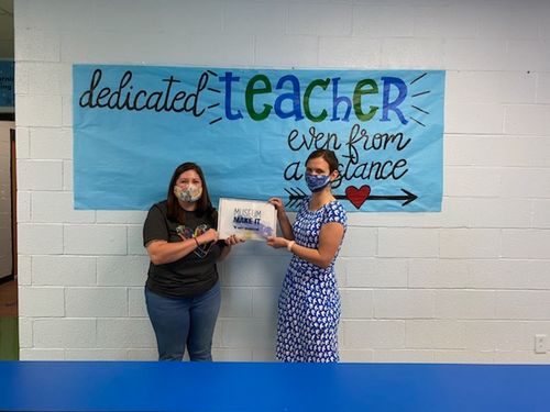 A Monogalia County art teacher (left) being presented with Make It Kits by Heather Harris