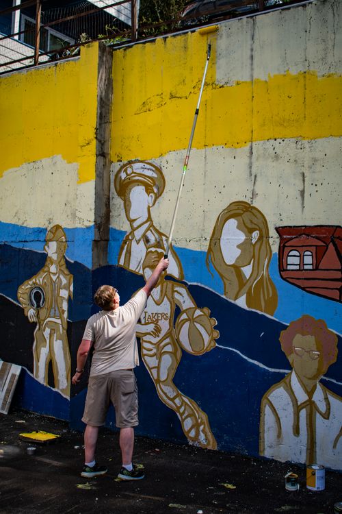 An art education student takes part in painting a mural on Beechurst Avenue