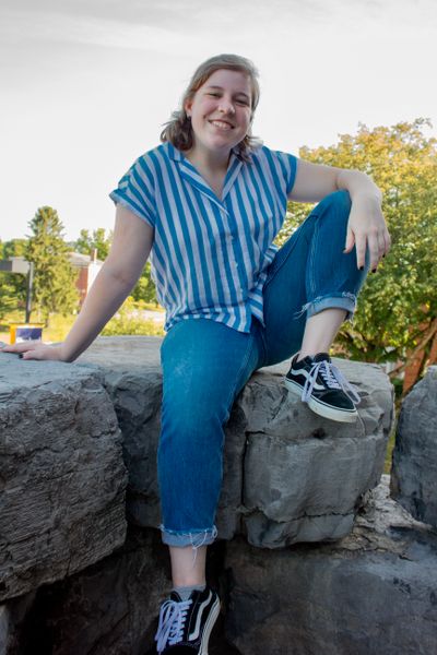 An image of Alison sitting on a rock with her knee propped up